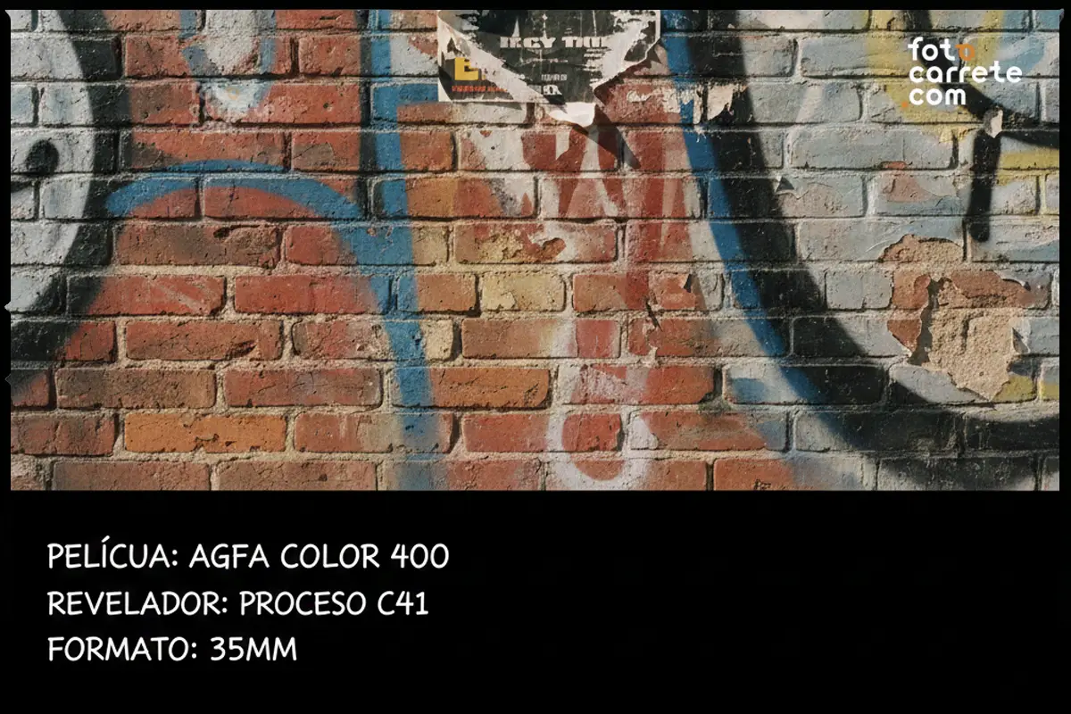 Pared de ladrillo con carteles rasgados y pintura, fotografiada con Agfa Color 400.