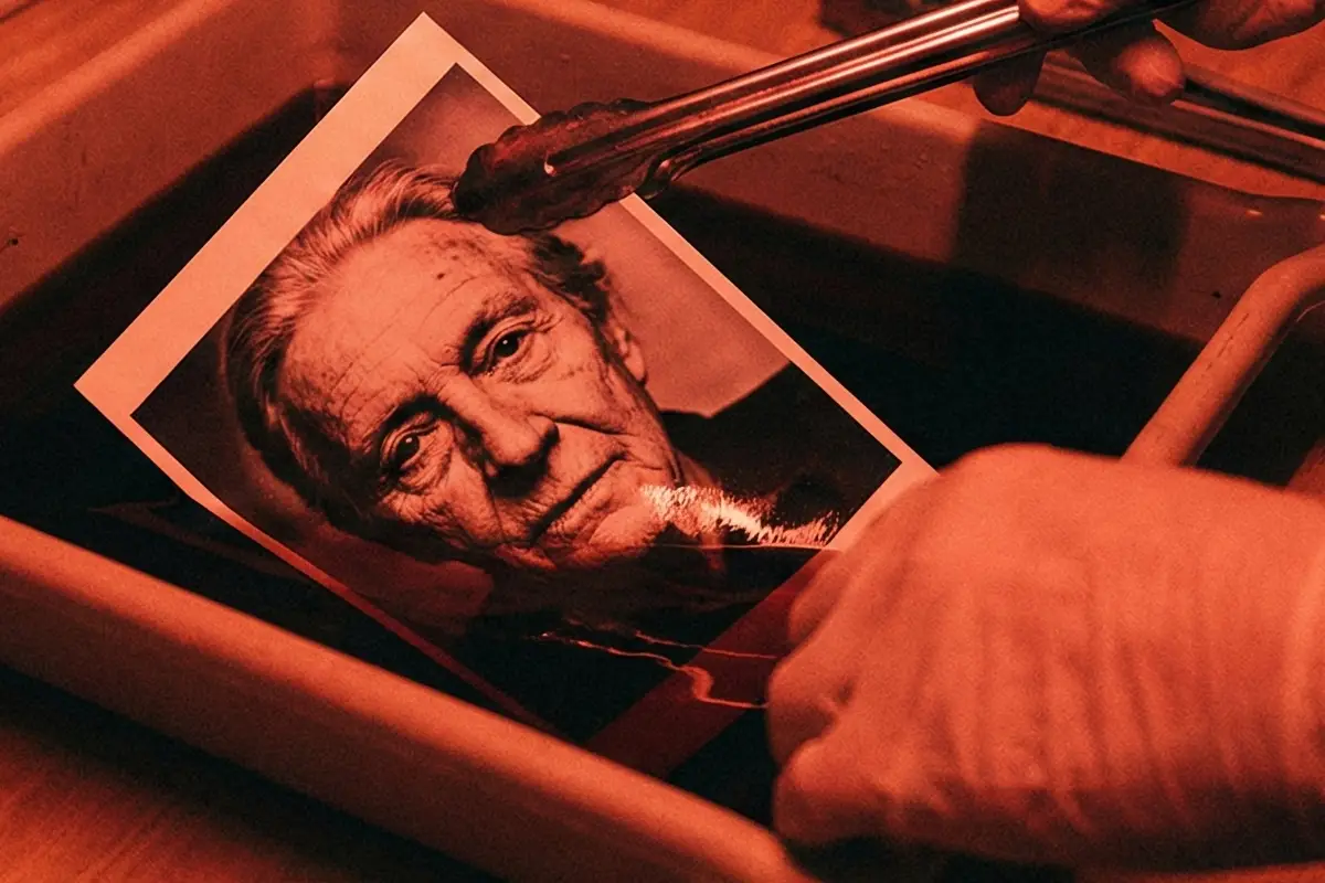 Proceso de revelado de papel Ilford en cubeta bajo luz de seguridad roja, positivado tradicional de retratos en blanco y negro.