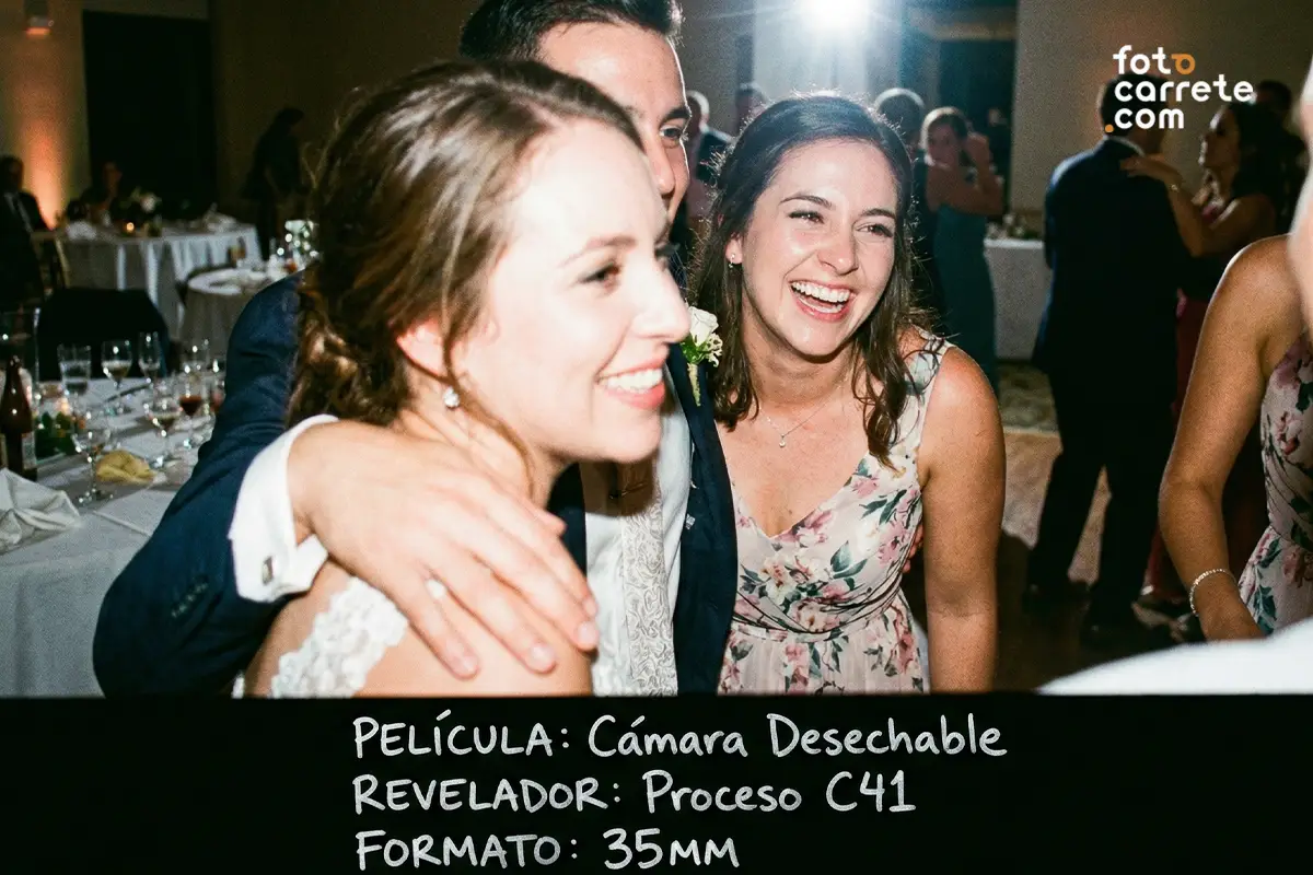 Invitados abrazándose y riendo en la celebración de una boda, foto tomada con cámara de un solo uso.