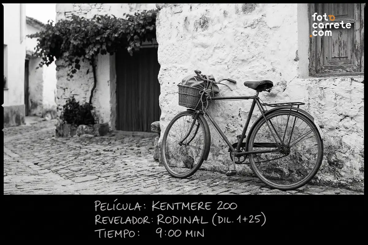 Fotografía de bicicleta clásica apoyada en fachada encalada tomada con carrete Kentmere 200 y revelador Rodinal.