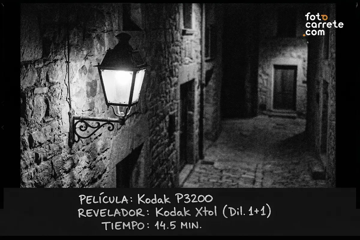 Fotografía urbana nocturna de un farol iluminado en callejón oscuro tomada con película Kodak P3200 y Kodak Xtol.