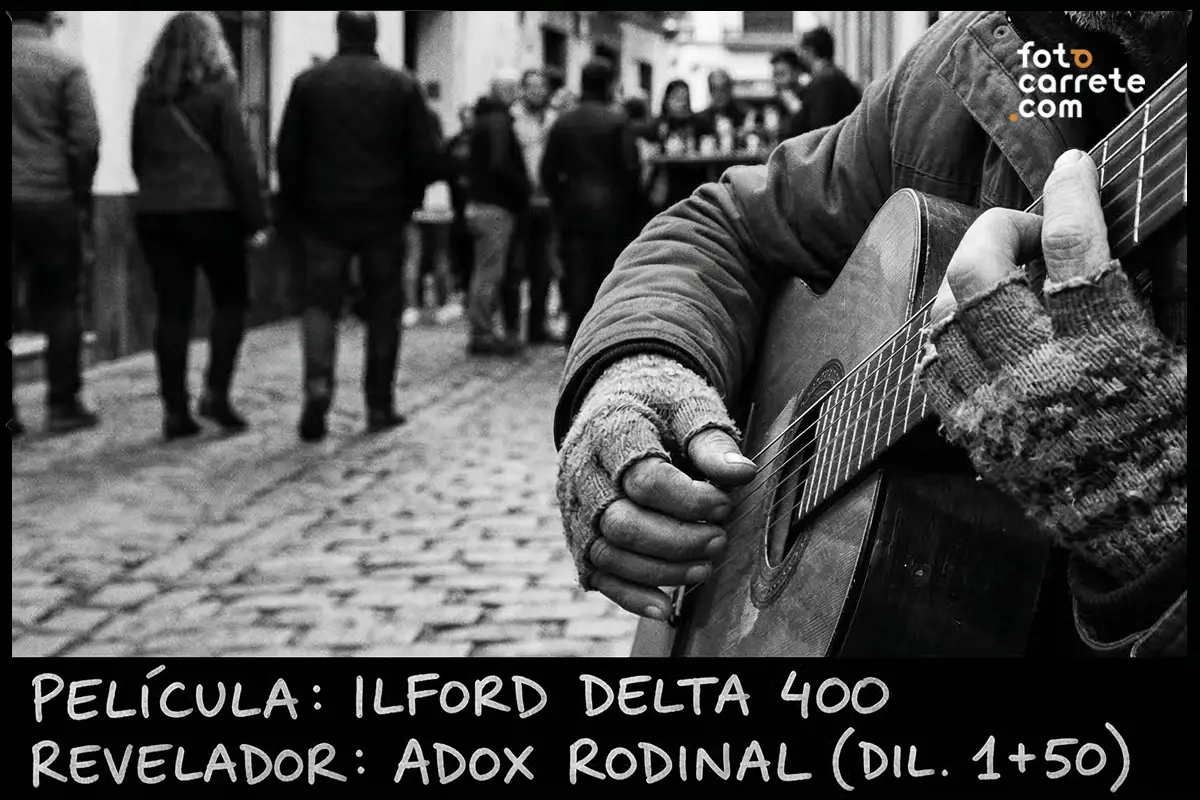 Detalle de manos de músico callejero tocando la guitarra en blanco y negro con carrete Ilford Delta 400.