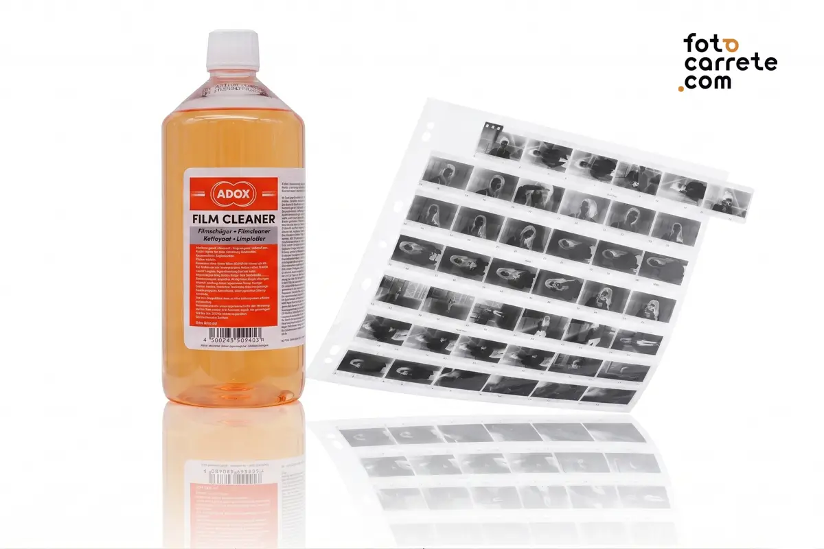 Botella de limpiador de película ADOX Film Cleaner junto a una funda con tiras de negativos de 35mm.