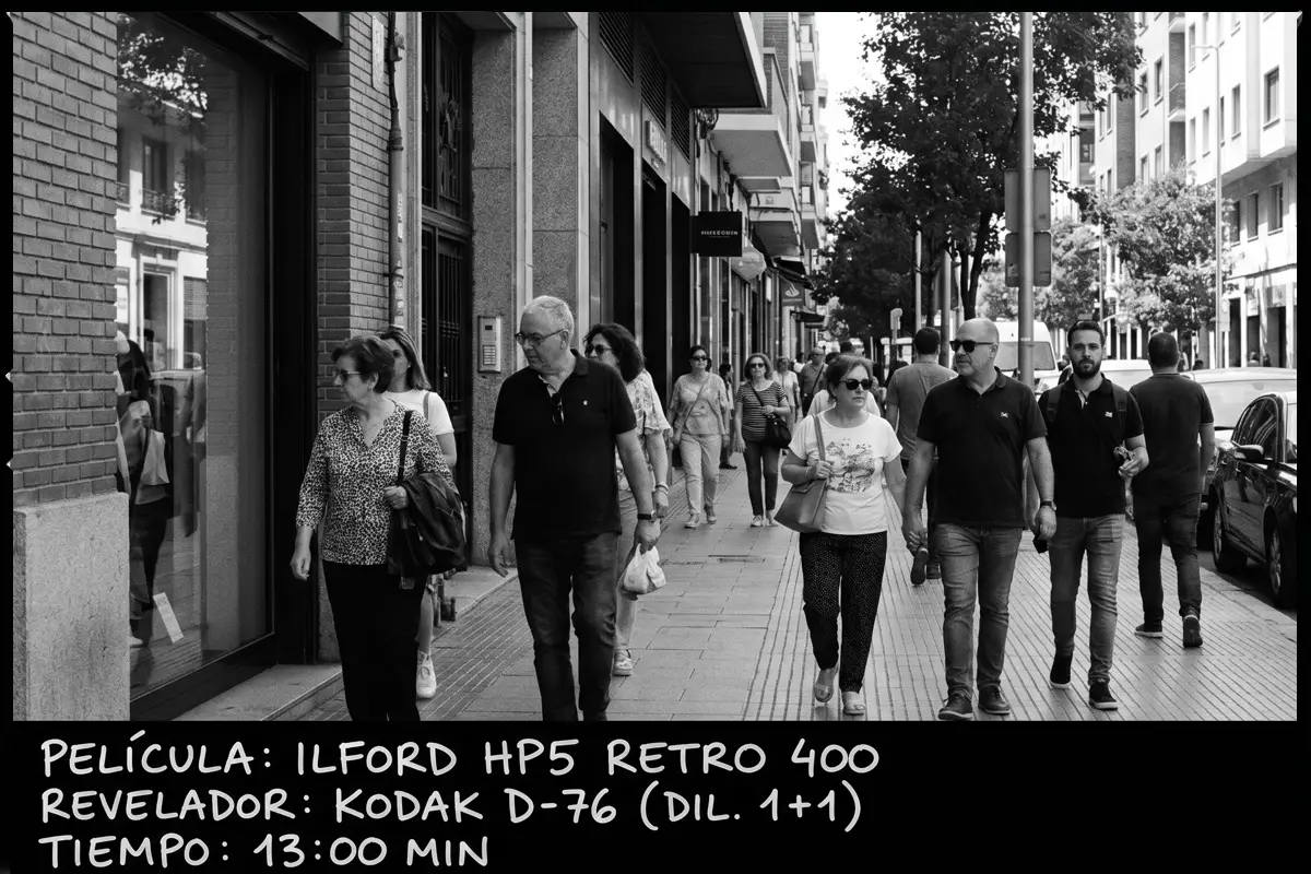 Grupo de personas caminando por la acera de una calle comercial en blanco y negro, Ilford HP5 Retro 400.